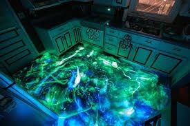 Kitchen with glowing epoxy resin floor, featuring swirling patterns in blue and green colors.